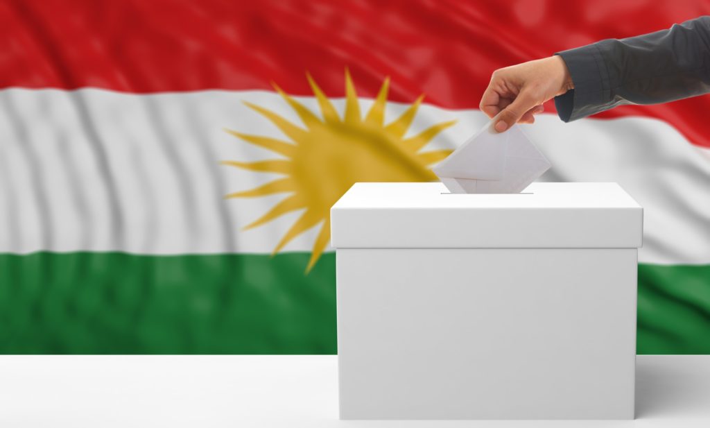 Woman's hand is voting with a waving Kurdistan flag background, 3d illustration