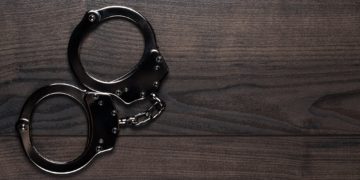 Handcuffs On Brown Wooden Table Background