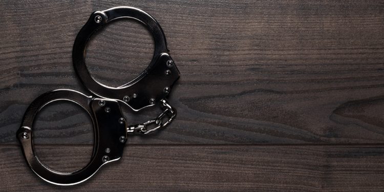 Handcuffs On Brown Wooden Table Background