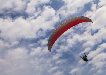 Flying paraglider on a background of blue sky and white clouds