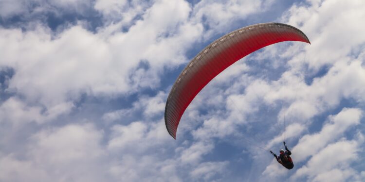Flying paraglider on a background of blue sky and white clouds