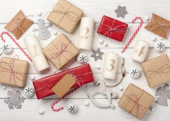 Advent candles, christmas decoration and gift boxes on white wooden background