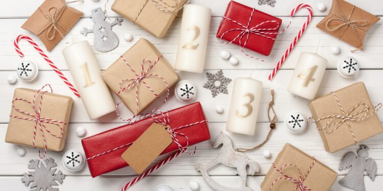 Advent candles, christmas decoration and gift boxes on white wooden background