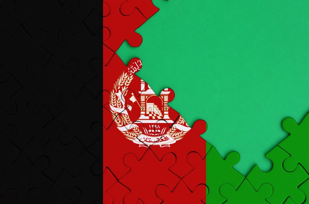 Afghanistan flag is depicted on a completed jigsaw puzzle with free green copy space on the right