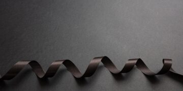 Black ribbon curl on black color background. Minimal black card template