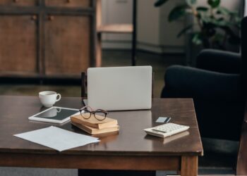 gadgets near cup, books and calculator on desk