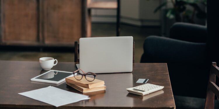 gadgets near cup, books and calculator on desk