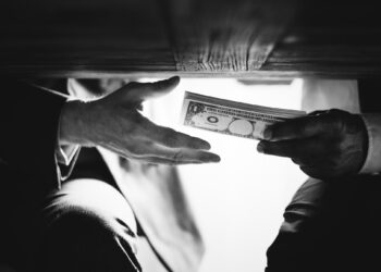 Hands passing money under table corruption bribery