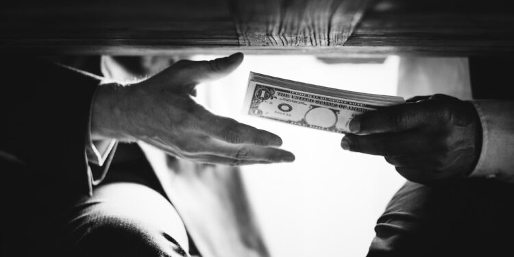 Hands passing money under table corruption bribery