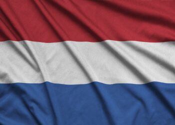 Netherlands flag is depicted on a sports cloth fabric with many folds. Sport team waving banner