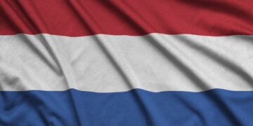Netherlands flag is depicted on a sports cloth fabric with many folds. Sport team waving banner