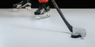 partial view of professional sportsman playing hockey on black