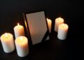 photo frame with black mourning ribbon and candles