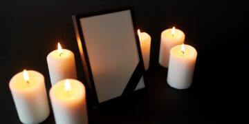 photo frame with black mourning ribbon and candles