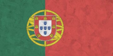 Portugal flag depicted in bright paint colors on old relief plastering wall close up