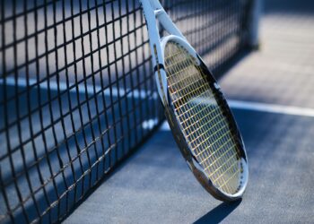 Tennis racquet is standing near tennis net