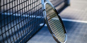Tennis racquet is standing near tennis net