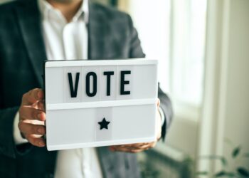 The word VOTE written on lightbox in men's hands. Election concept