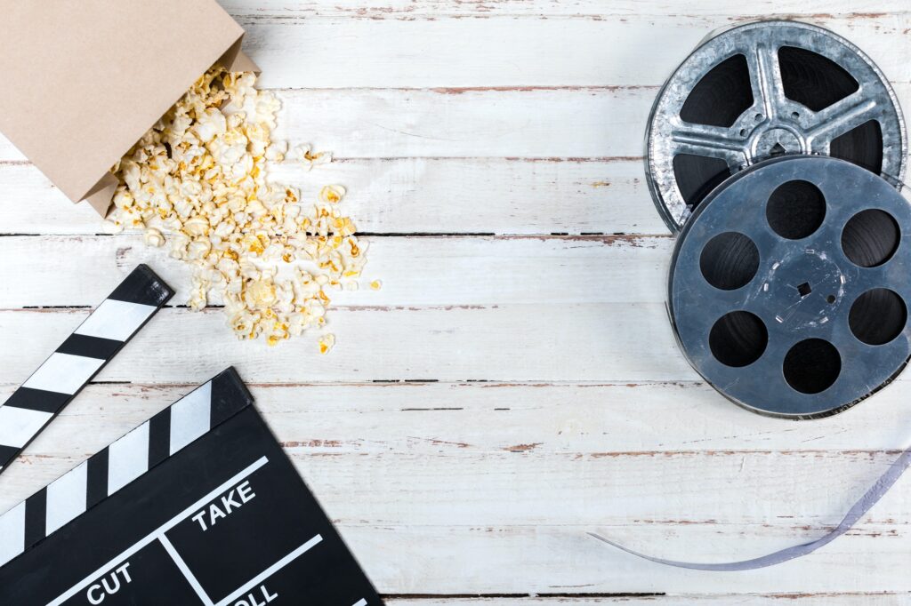 Top view of film reels, popcorn and movie clapper on wooden table, Movie time concept