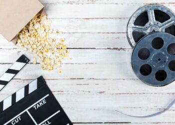 Top view of film reels, popcorn and movie clapper on wooden table, Movie time concept