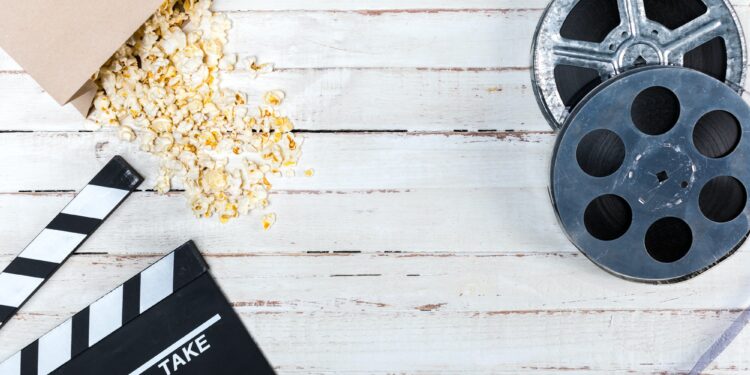 Top view of film reels, popcorn and movie clapper on wooden table, Movie time concept