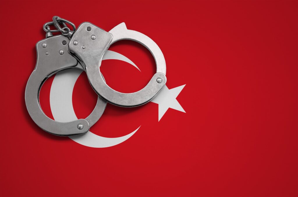 Turkey flag and police handcuffs. The concept of crime and offenses in the country.