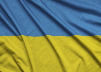 Ukraine flag is depicted on a sports cloth fabric with many folds. Sport team waving banner