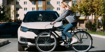 woman riding bicycle while crossing road with driver in car