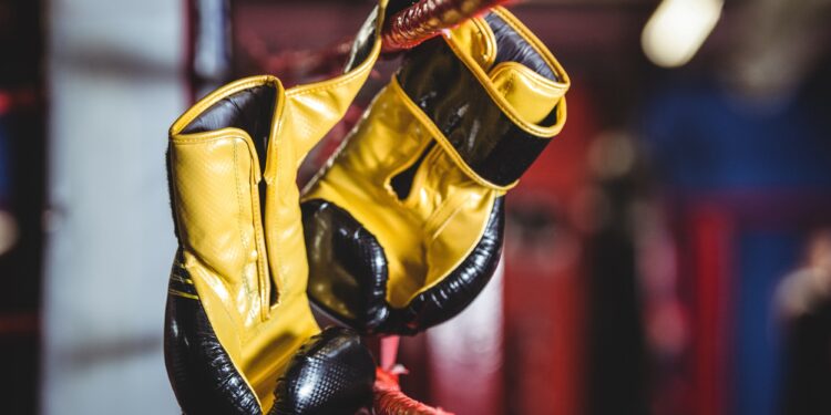 Yellow boxing gloves hanging off the boxing ring